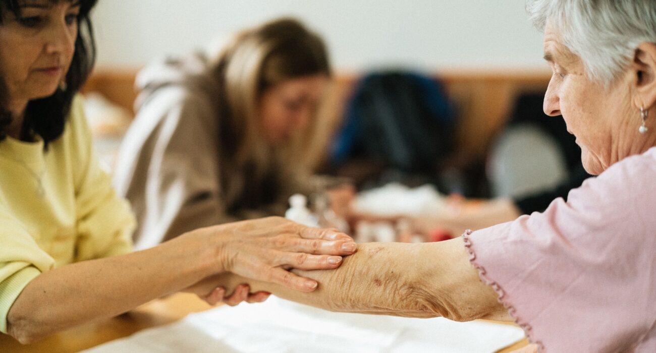 Caregiver gently supporting an elderly woman's arm while walking, helping prevent falls at home