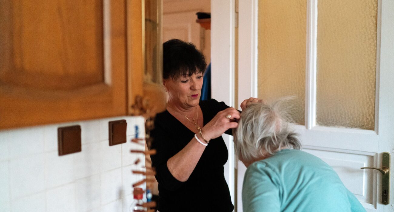 Professional in-home caregiver assisting a senior woman with personal care in a comfortable home setting