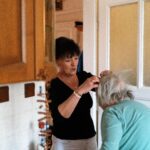 Professional in-home caregiver assisting a senior woman with personal care in a comfortable home setting