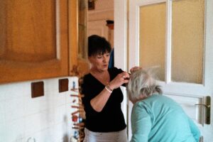 Professional in-home caregiver assisting a senior woman with personal care in a comfortable home setting