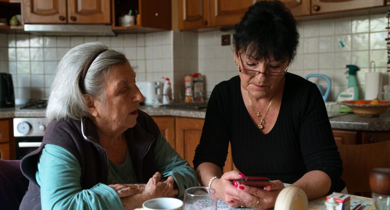 Senior woman and her in-home caregiver sharing a warm moment in a cozy kitchen setting