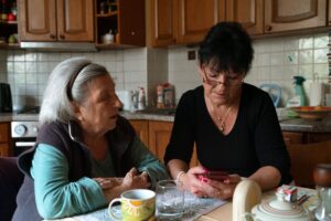 Senior woman and her in-home caregiver sharing a warm moment in a cozy kitchen setting