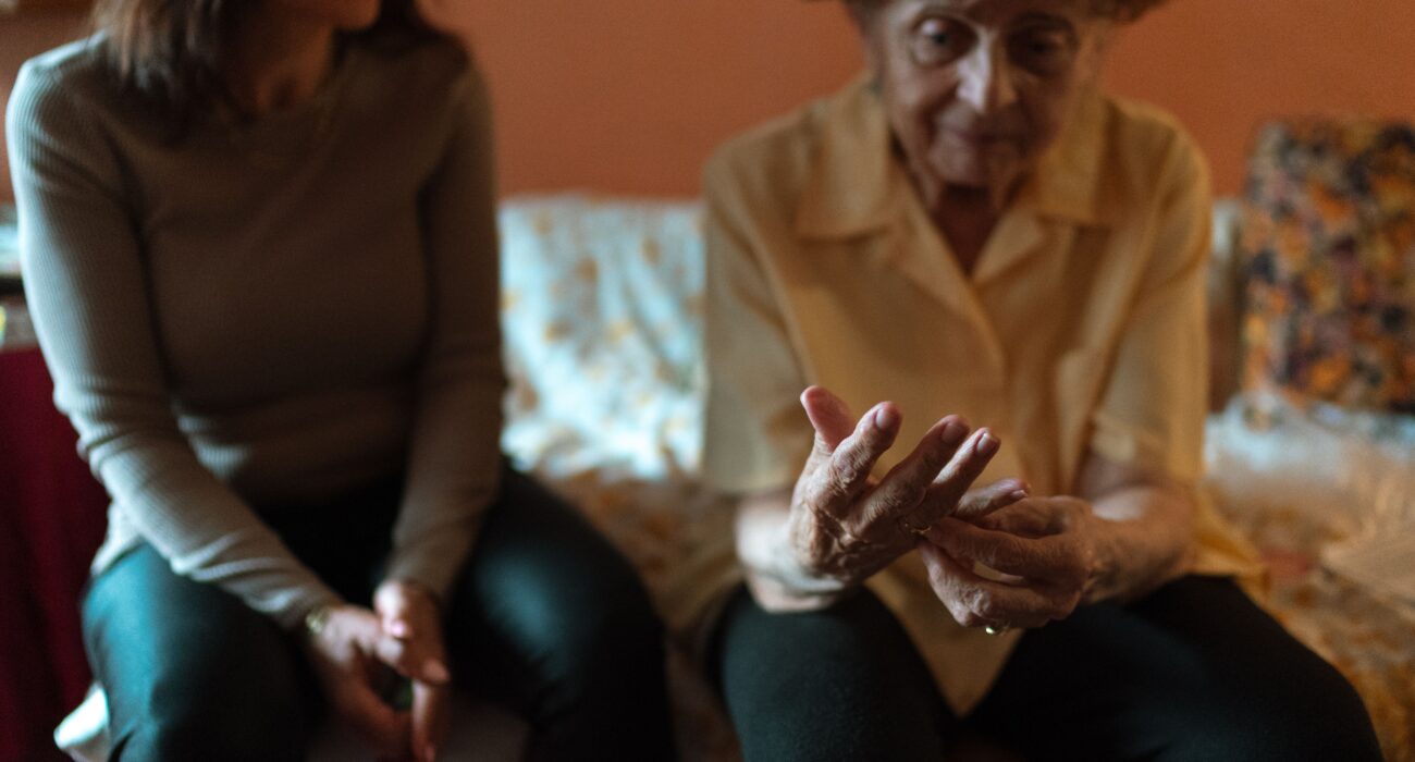 Elderly woman and her caregiver sharing a comfortable moment together at home, illustrating home care versus facility care