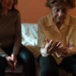 Elderly woman and her caregiver sharing a comfortable moment together at home, illustrating home care versus facility care