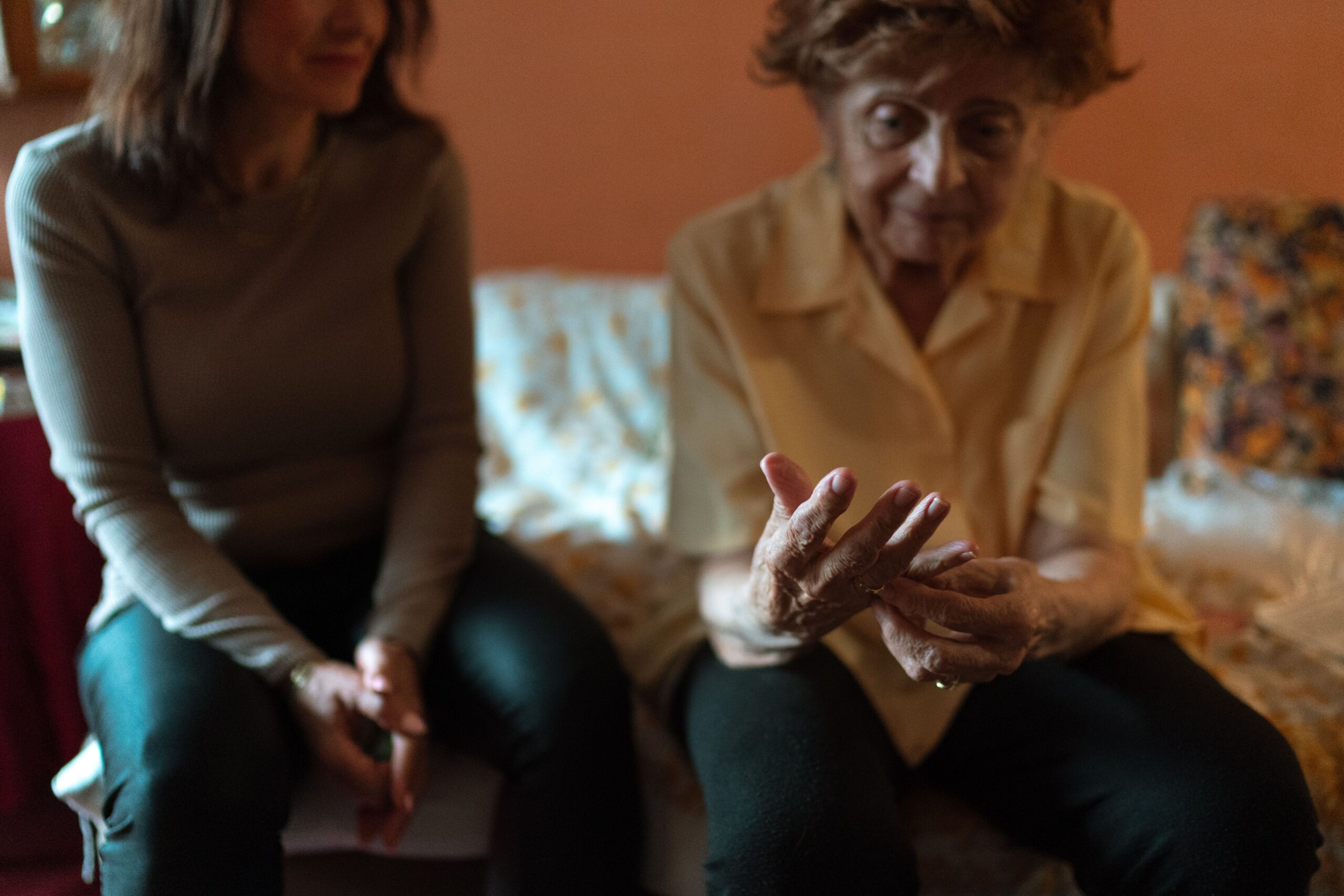 Elderly woman and her caregiver sharing a comfortable moment together at home, illustrating home care versus facility care