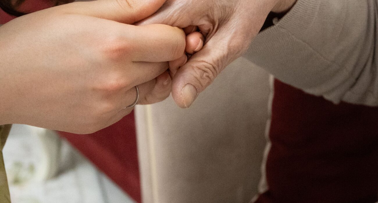 Adult daughter gently holding her aging mother's hand, recognizing signs she may need help at home