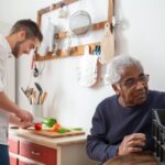 A caregiver and senior man preparing a meal together in the kitchen, an example of the companionship and household support home caregivers provide