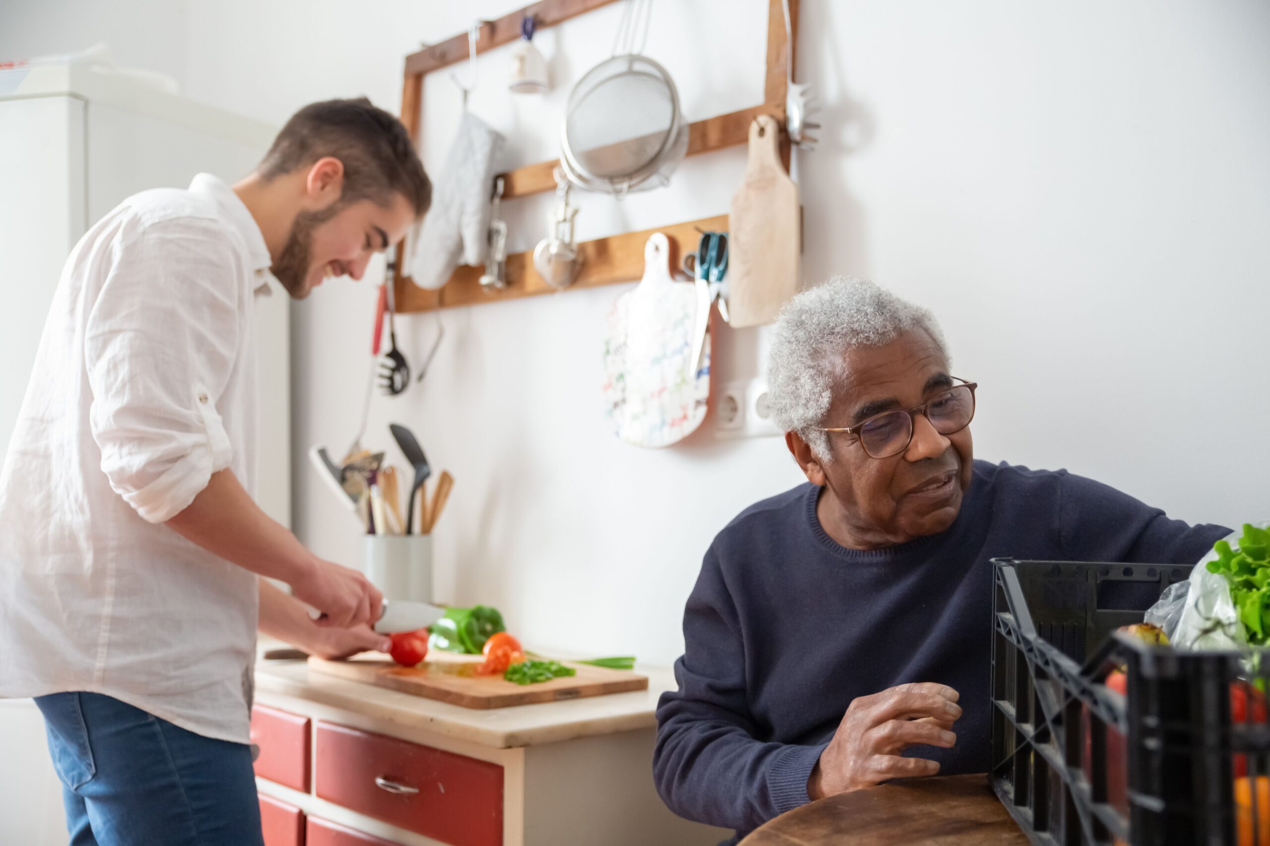 A caregiver and senior man preparing a meal together in the kitchen, an example of the companionship and household support home caregivers provide