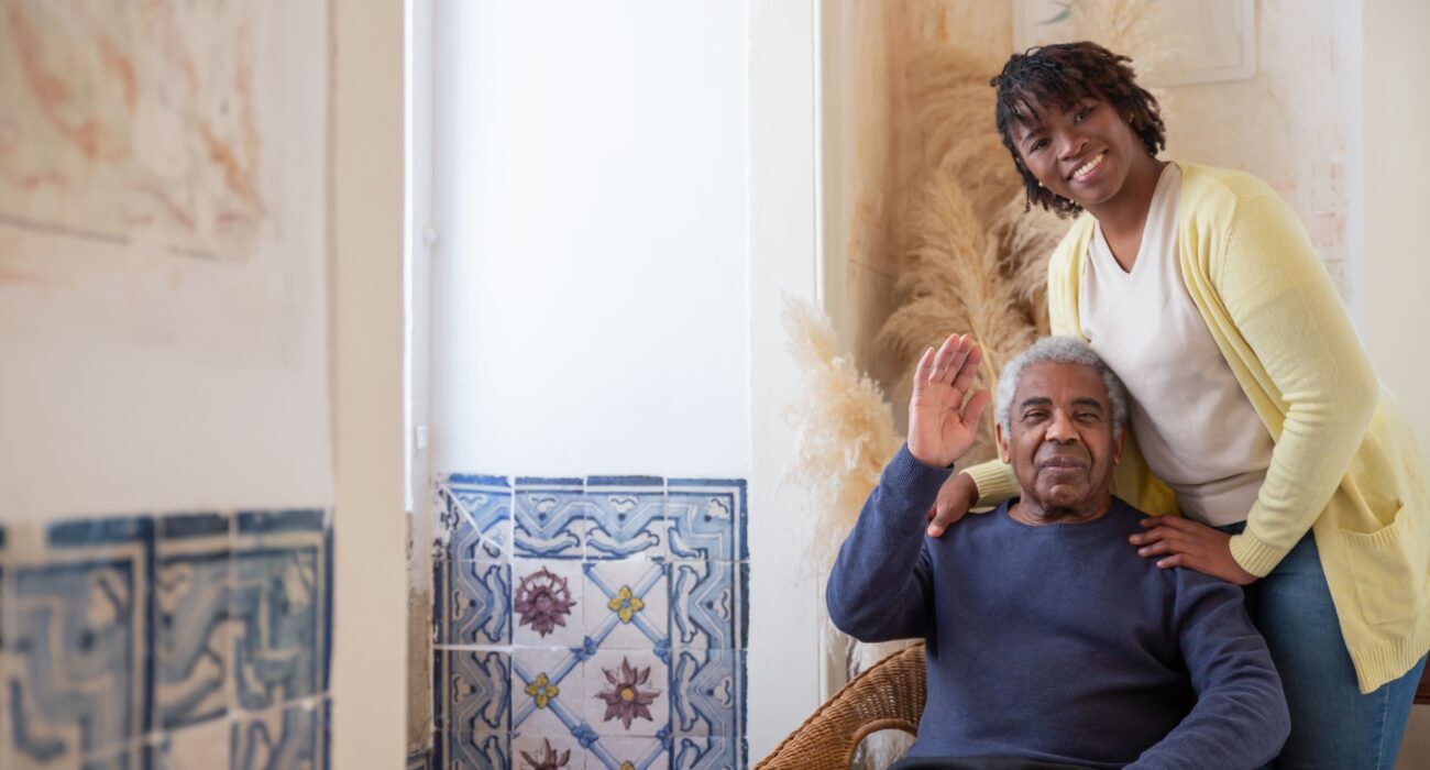 An elderly man and his adult daughter sharing a calm, warm moment together in a living room, reflecting patient communication in dementia care