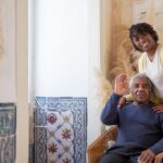 An elderly man and his adult daughter sharing a calm, warm moment together in a living room, reflecting patient communication in dementia care