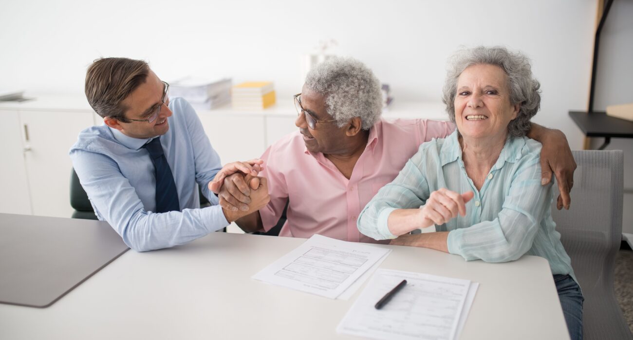 A senior couple meeting with a consultant, discussing questions and documents, representing the kind of informed conversation families should have before choosing a home care agency